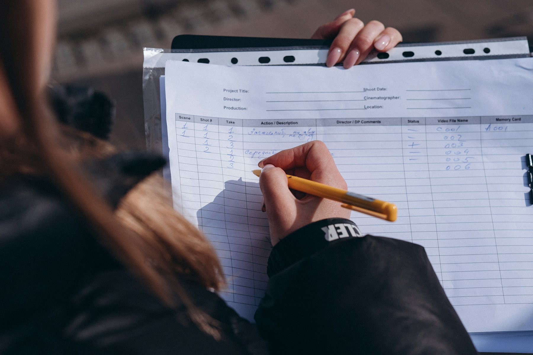 Hands filling in a paper register with a pencil