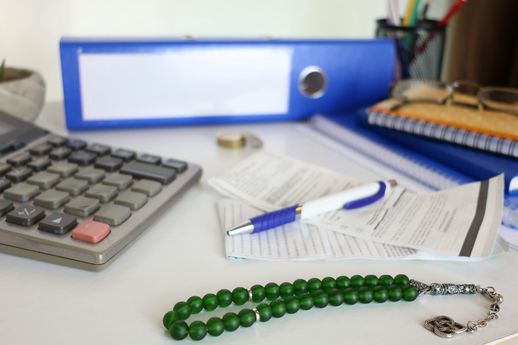 A calculator, papers and a string of beads on a desk